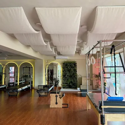 A wide view of the studio, showcasing the spacious layout with multiple reformers, a Cadillac, and a Wunda chair. The design promotes a feeling of openness and calm.