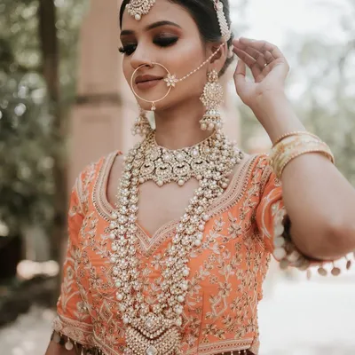 A detailed close-up of a stunning multi-layered pearl and polki rani haar, paired with a matching nath and maang tikka. This is the ultimate accessory for a regal bridal shoot.