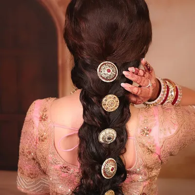 A detailed shot of a stunning bridal braid. This thick, textured braid is adorned with traditional gold accessories, creating a look that is both modern and timeless.