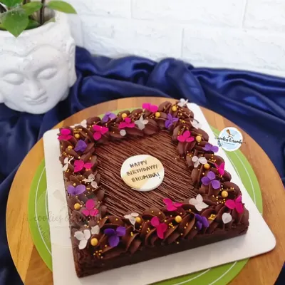 A rich, 8-inch Hazelnut Brownie Cake. I decorated the edges with chocolate frosting and a sprinkle of edible butterflies and flowers for a pop of color.