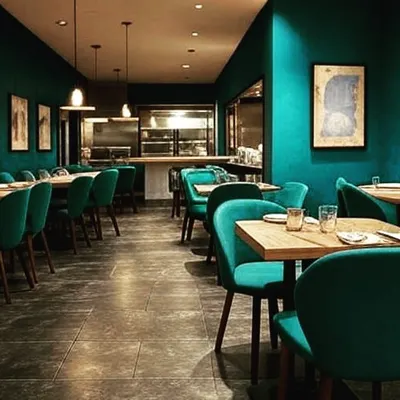 A bold and intimate restaurant interior featuring deep teal walls and matching velvet chairs. The warm lighting and curated artwork create a sophisticated and moody dining atmosphere. Note: Image 67 is a similar view.