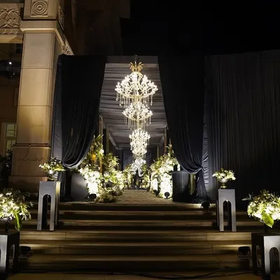 The entrance to our 'Black Luxe' Sangeet. Grand chandeliers, dramatic black drapes, and soft white blooms created a luxurious and moody setup for a night to remember.
