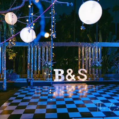 The stage is set for a night of music and dance. A classic checkered dance floor, personalized marquee letters, and dramatic lighting create an atmosphere of chic sophistication.