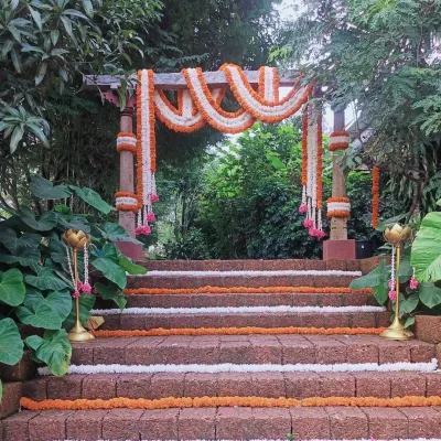 A simple yet beautiful entrance for an outdoor wedding. We used a rustic wooden arch and adorned it with garlands of orange and white marigolds. The steps are lined with flowers, creating a warm and traditional welcome for guests.