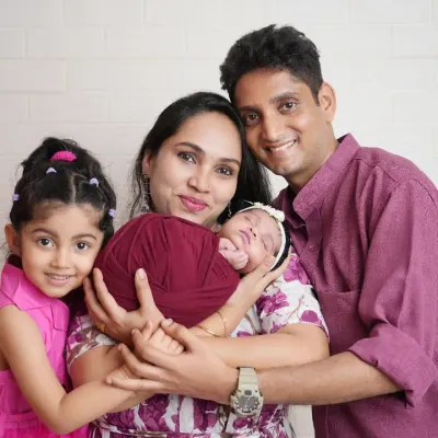 And then there were four! This beautiful family portrait captures the joy of a growing family. The older sister is so excited to meet her new sibling, a precious memory for everyone.