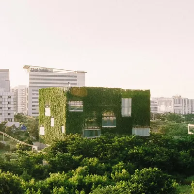 The KMC Headquarters stands as a verdant cube amidst the concrete and glass of Hyderabad. This living facade is not just an aesthetic choice but a high-performance building skin that actively cools the interior and connects the workspace to the natural world.
