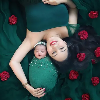 This is one of my absolute favorite poses for a mother and newborn. The rich green fabric and scattered red roses create a stunning, artistic portrait that feels like a painting. It’s a beautiful celebration of motherhood.
