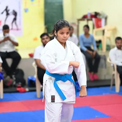 A young student demonstrates a strong, focused stance during her karate training. Her blue belt signifies her progress and dedication to the art.