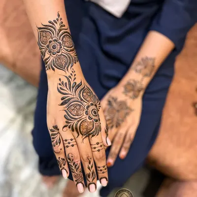 A classic and elegant Arabic henna design. This style features bold floral and vine patterns that flow diagonally across the hand, leaving some skin exposed for a beautiful contrast.