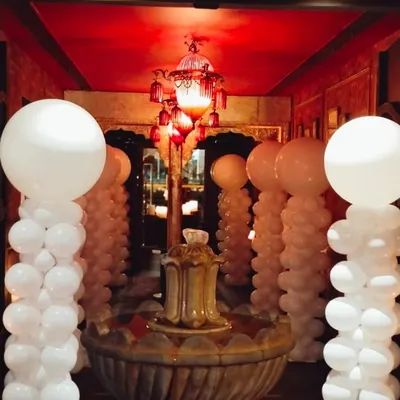 An elegant and dramatic entrance created with tall white balloon pillars. This white-themed decoration transforms a hotel corridor into a sophisticated event space, perfect for weddings or upscale parties.