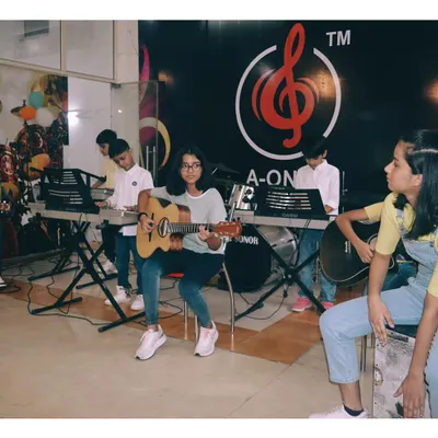A group of students learning guitar and keyboard together. This setup mimics a real band, teaching them how to play in sync and listen to each other.