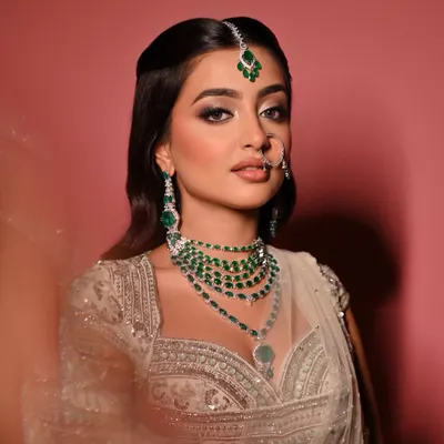 A close-up of the "Moonlit Majesty" look. The focus here is on the silver-toned smokey eye, sharp winged liner, and a soft nude lip, all framed by stunning emerald jewellery.