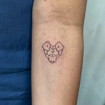 A fine-line tattoo of three little bears in a heart, symbolizing the unbreakable bond between three sisters. This minimalist design is a permanent reminder of their shared childhood and lifelong unity.