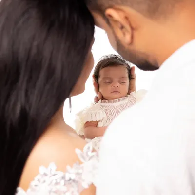 A creative family portrait focusing on the newest member, held securely in her parents' loving hands. A beautiful way to symbolize that the baby is the center of your world.