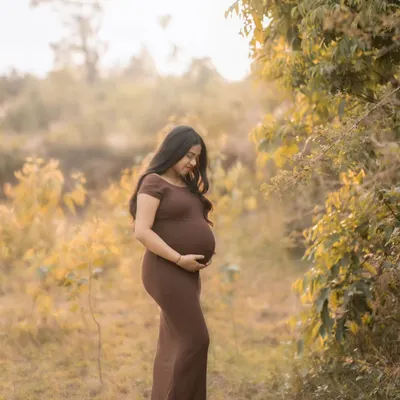 A peaceful solo portrait in a beautiful brown dress, surrounded by the soft, warm light of the setting sun in a natural field setting.