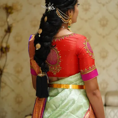 A detailed view of a traditional South Indian bridal braid. This hairstyle features intricate weaving and is adorned with classic gold accessories, creating a look of timeless elegance.