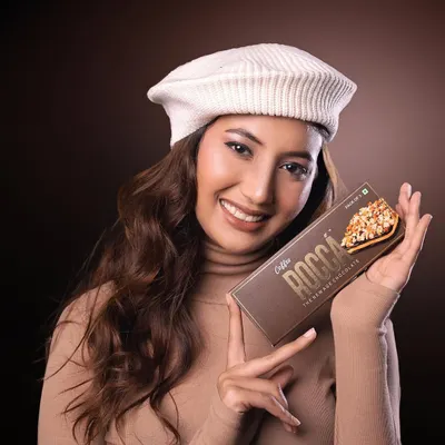 A vibrant commercial portrait for Rocca Chocolates. The model's cheerful expression and direct engagement with the product create an appealing and effective advertisement.