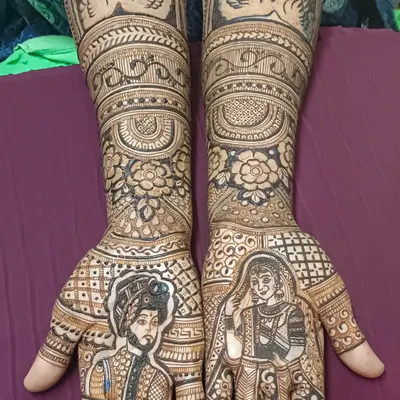 A perfect example of story mehendi, with portraits of the bride and groom on each palm. The design is completed with swan motifs and floral patterns, creating a beautiful narrative of their union.