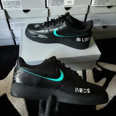 Custom Nike Air Force 1s designed with a Lewis Hamilton Mercedes AMG F1 theme. This pair features sponsor logos like INEOS and UBS, showcasing our ability to execute precise corporate branding.