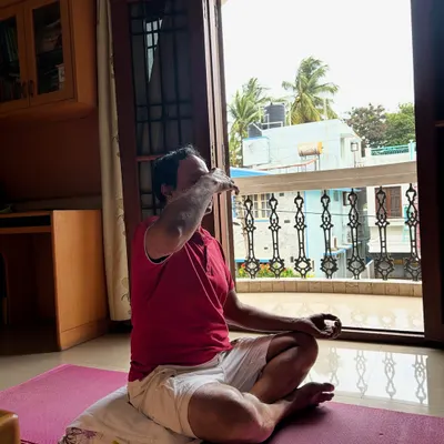 A client practices Nadi Shodhana pranayama (alternate nostril breathing) during an at-home personal training session, focusing on stress reduction and mental clarity.