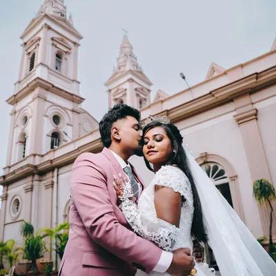 A classic wedding portrait of the groom kissing his bride on the forehead, with the church spires rising majestically in the background.