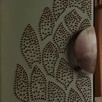 A close-up of the custom-designed door handle and the 3D embellished fabric of the entrance. The half-round brass handles meet at the center of the floral motif, anchoring the piece with a detail that is both functional and symbolic.