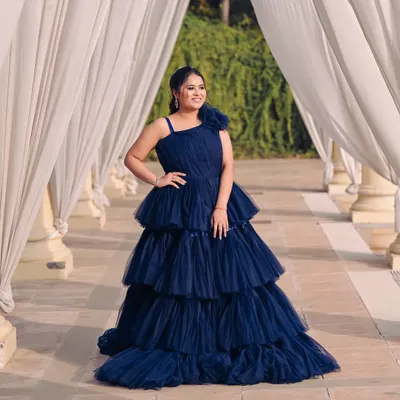 A beautiful shot of a client ready for her pre-wedding shoot in a stunning navy blue tiered gown. The makeup is soft and glamorous, designed to look flawless in the golden hour light.