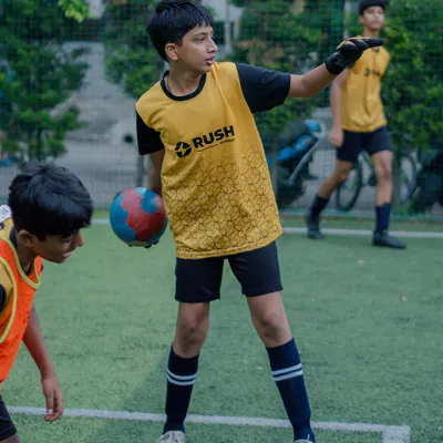A young player in a goalkeeper bib prepares to distribute the ball, showing the versatility we encourage in our players to understand all aspects of the game.