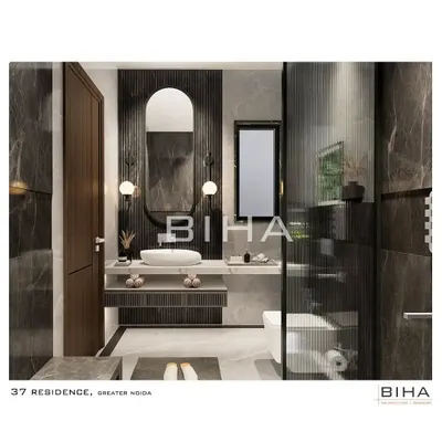 This luxury washroom in Greater Noida features a sophisticated palette of grey marble and dark wood fluting. An arched mirror and contemporary globe sconces soften the clean lines of the floating vanity, which includes open shelving for easy access to essentials.
