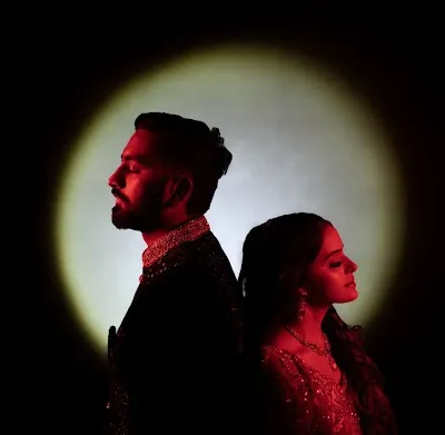 A creative couple portrait using a spotlight effect. The dramatic lighting and back-to-back pose create a modern and artistic image.