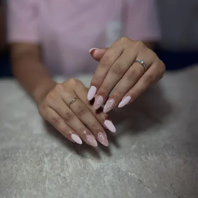 A delicate and elegant design on almond-shaped nails, featuring a soft pink base with intricate white line art.