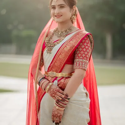 My beautiful bride Rachana, looking radiant in her red and white wedding saree. The custom blouse features a traditional check pattern with delicate embroidery on the sleeves.