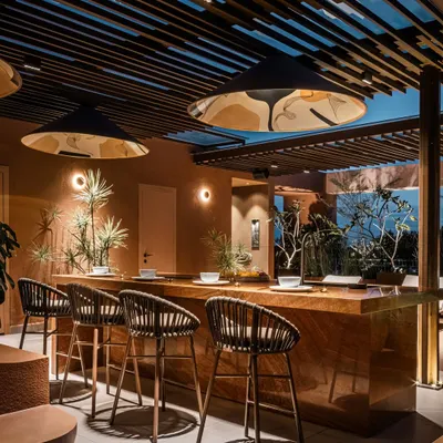 The monolithic bar at the Terra Gardens project, crafted from a single piece of sandalwood traver onyx marble. This outdoor kitchen entertainment zone is designed for hosting, with ample counter space and dramatic lighting.