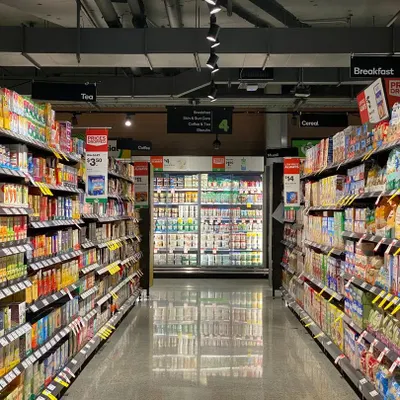 The central aisle of the Shop24 Hours convenience store in Delhi. Our layout ensures clear sightlines to different product categories like 'Breakfast' and 'Tea', making navigation easy for shoppers.