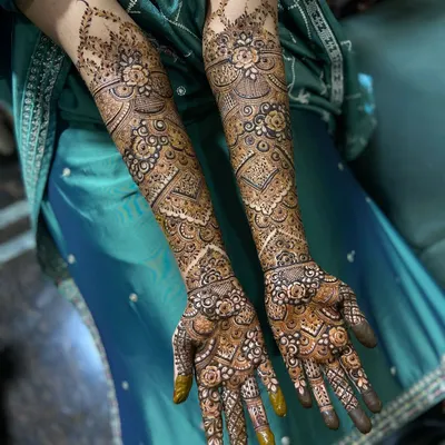 A complete view of a full-coverage engagement henna design. The patterns are symmetrical yet unique on each arm, creating a cohesive and stunning bridal look.