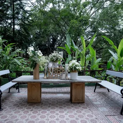 A quiet seating area with a stone table and benches, set amidst the lush greenery of our gardens, perfect for guests to relax.
