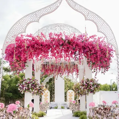 A beautiful floral archway created for a daytime celebration. The white structure is adorned with vibrant pink bougainvillea, creating a stunning entrance and photo opportunity.