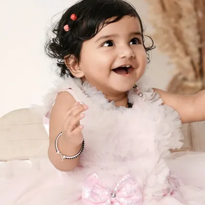 The pure, uncontainable joy of a baby's laugh. This close-up shot of a happy baby girl in a beautiful pink dress perfectly captures her delightful personality.