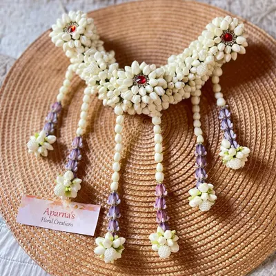 A beautiful floral hair brooch made from white jasmine buds. This piece can be worn with a bun or braid and is accented with red stones and delicate hanging strands.