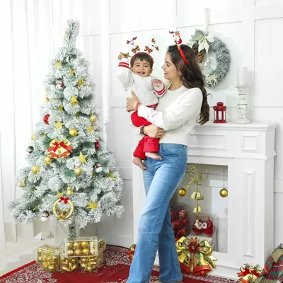 A full-length view of our Christmas-themed studio setup, showing a mother lifting her child in joyful celebration. The festive decor, from the frosted tree to the fireplace, creates a complete holiday scene for memorable family photos.