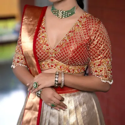 A close-up of a bridal blouse with a stunning V-neck and intricate jaal (net) embroidery. The floral motifs on the border add a touch of timeless elegance.