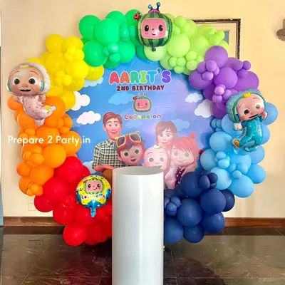 A vibrant Cocomelon themed birthday party featuring a full rainbow balloon ring. This setup includes a custom backdrop with all the main characters and is perfect for a colorful and fun second birthday celebration.