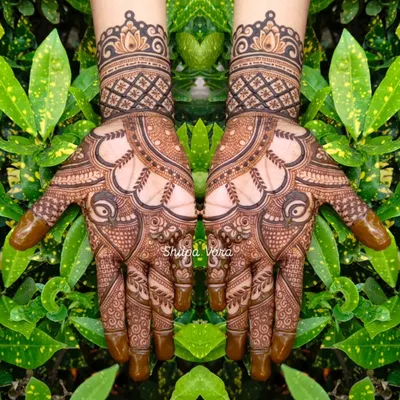 A symmetrical design featuring peacocks and traditional Indian motifs, set against a natural green background.