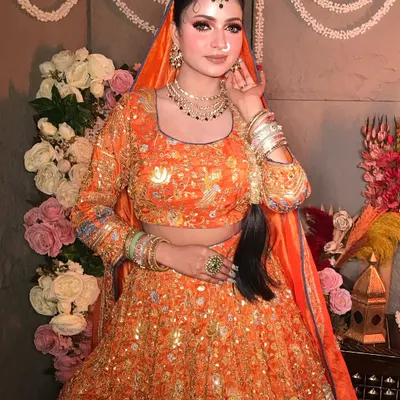 "Subhanallah." A beautiful portrait in a vibrant orange lehenga. The makeup is soft and glowing, with a focus on defined eyes and a traditional maang tikka.