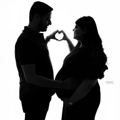 A classic and sweet silhouette. The heart-hands pose against a bright white background creates a simple, iconic image celebrating your love and new arrival.