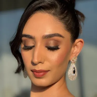 A close-up of this stunning cocktail look, captured in the golden hour light. Notice the seamless blend of the smokey eyeshadow, the precise highlight on the cheekbones, and the soft matte lip. This is HD makeup designed to look impeccable from every angle.