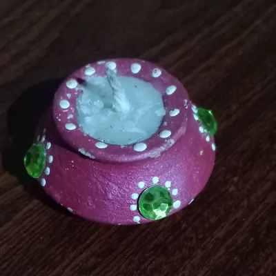 A close-up of my handmade terracotta diya candle. I paint each pot and fill it with wax to offer a modern, reusable, and eco-friendly alternative to disposable diyas for Diwali.