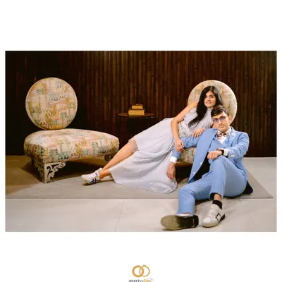 A wide, editorial-style shot that feels like a page from a high-fashion magazine. The composition, the furniture, and their poses all come together to create a cool, stylized portrait.