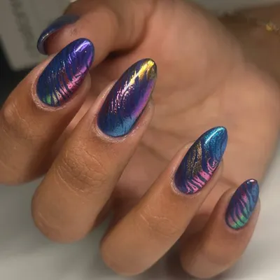 A stunning multi-chrome nail art design. The metallic polish shifts between shades of blue, purple, and gold, with a subtle zebra-like pattern etched on top for added texture.