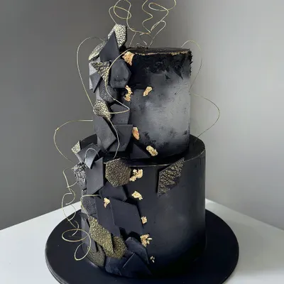 Black and gold never go out of fashion. A modern and dramatic two-tiered cake with a concrete texture, gold leaf, and abstract chocolate shards.